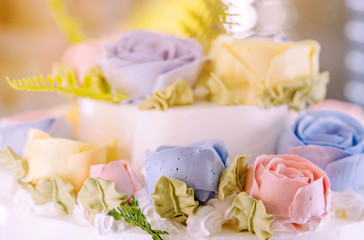 Close up to wedding cake decorated with roses and flowers for the groom and the bride in the wedding day.