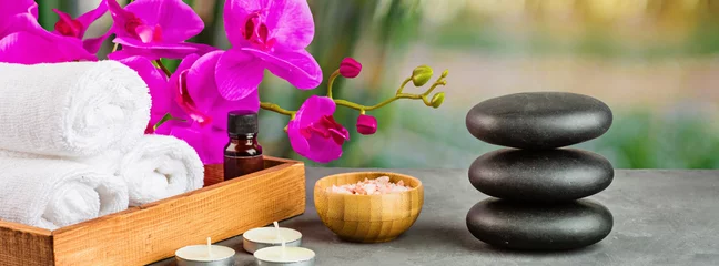 Fotobehang Spa hot spa-stenen voor massagebehandeling, orchideebloem, handdoeken, kaarsen en zeezout op groene achtergrond met bamboe. Elegante en luxe spa. bespotten, sjabloon. Gezondheids- en schoonheidsverzorgingsconcept