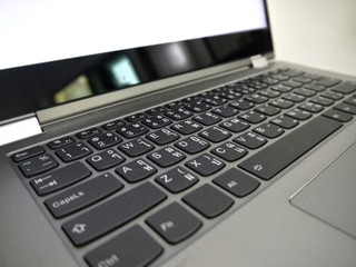 Silver grey laptop and black keyboard, English with Thai alphabet letters, with a white screen.