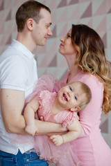 happy little girl in pink dress with mom and dad