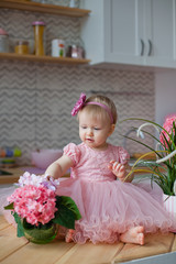 little girl in pink dress in the kitchen with a bouquet of flowers
