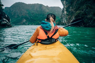 Girl kayaking on the seaside of Halong bay in Vietnam. Woman rowing oars in the boat. The view from...