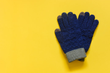 top view of blue and green color touchscreen glove on yellow background, copy space, flat lay