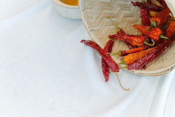 Dry red chilli pepper out of bamboo basket on whit cloth with copy space, food ingredient