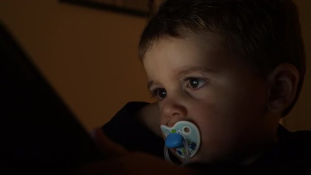 Close up of toddler watching and interacting with tablet. Static