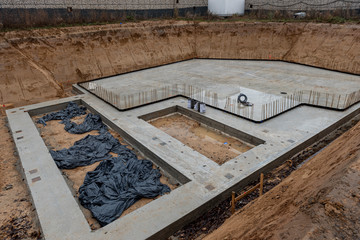 Die Baugrube mit Betonfundament eines Einfamilienhauses