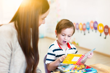 Children reading a book with teacher in a classroom. Children and learning concepts.