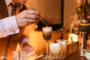 Bartender putting a garnish on a cocktail glass with a drink. Lifestyle horizontal image. Selective focus.