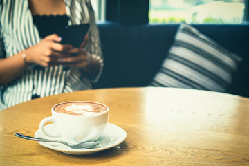businesswomen working with laptop and hand catch cup of coffee. A mobile phone is on the table near the laptop.