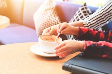 Children use coffee spoon. A cup of coffee is on the table in the coffee shop.