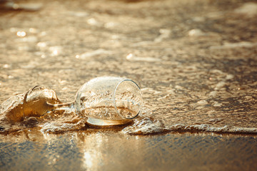 glass wine on the beach and sea water flow in golden hour