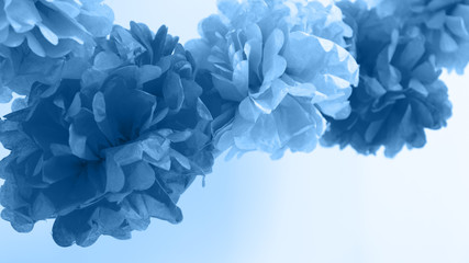 Obraz premium Paper flowers at the baby shower party. Baby shower celebration concept. Festive party background. Horizontal, wide screen format, toned in classic blue