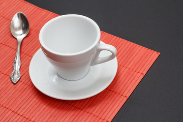 Empty coffee cup on red napkin and black background.