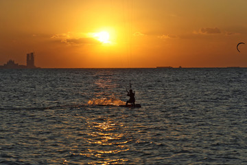  A lone wind surfer rides the sea against the backdrop of a golden sunset dubai
