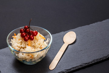 Fermented cabbage with herbs and spices in glass bowl on the black background