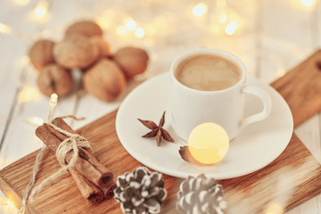 Fototapeta na wymiar Cozy autumn or winter concept. Cup of coffee with a garland lights and decoration/