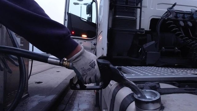 Close up shot of a HGV driver refueling a lorry and walking away.