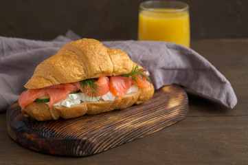 croissant with salmon and cream cheese on a wooden Board.