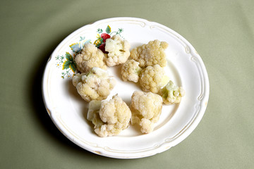 Cooking. Broccoli on white plate and green background
