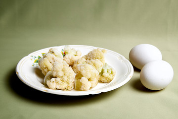 Cooking. Broccoli on white plate and green background