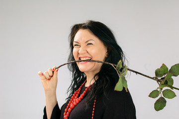 Pretty Middle-aged Woman with Rose Dancing in Studio in Black Dress and Red Necklace