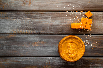 Trendy dessert - salted caramel - melted and cubes on dark wooden background top view frame copy space