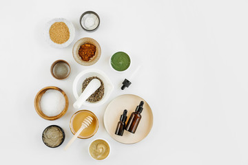 Beauty treatment ingredients for making homemade skin care cosmetic mask. Various bowl with clay, cream, essential oil and natural ingredients  on white table background. Organic spa cosmetic products