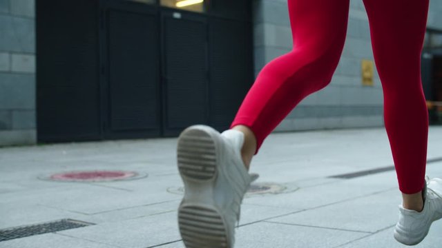 Close up female legs jogging on urban street. Athlete woman legs running outdoor