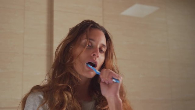 Very lazy young woman brushing her teeth