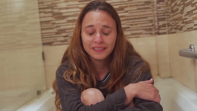 Beautiful young woman crying on the bathtub