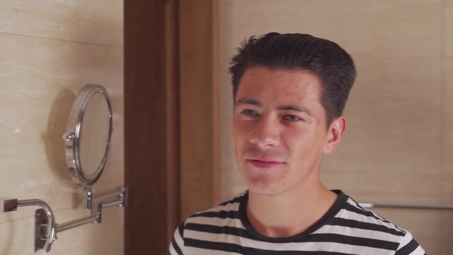 Young man brushing his hair in front of the mirror