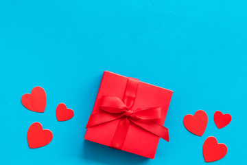 Gift to a sweetheart on Valentine's Day. Red present box near hearts on blue background top-down...
