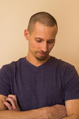 Portrait of a brooding young man in a blue or purple photoball against a beige wall