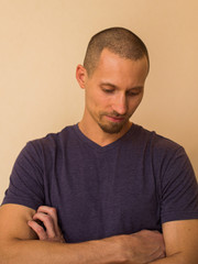 Portrait of a brooding young man in a blue or purple photoball against a beige wall