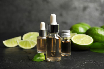 Lime essential oil and cut citrus fruits on black table