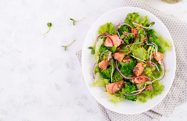 Salad of baked fish salmon, broccoli, lettuce, red onion and dressing. Fish menu. Seafood - salmon. Top view, overhead