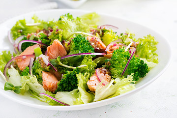 Salad of baked fish salmon, broccoli, lettuce, red onion and dressing. Fish menu. Seafood - salmon.