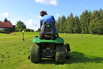 Cutting the grass of  on a tractor lawn mower - Powered by Adobe