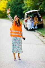 Woman in orange reflective vest is catching car having broken ca