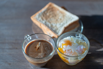 Thai style hot coffee with soft boiled eggs  and bread  on wooden table background