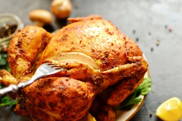 Baked whole chicken curry. Festive dish on a dark background. Baked chicken sliced ​​with a fork.