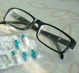 Fototapeta na wymiar Glasses lie next to foil capsule packaging. Partly used package. Healthcare and medicine concept, flu season