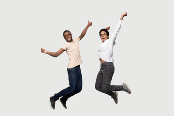 Energetic euphoric african american couple friends jumping with raised hands.