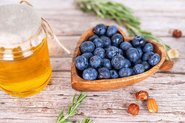 blueberries in a wooden plate with a jar of honey