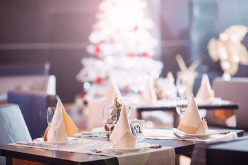 Table setting in the restaurant. Christmas tree on the background.