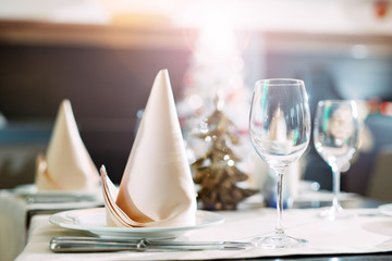 Table setting in the restaurant. Christmas tree on the background.