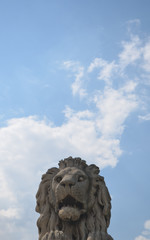 Stone sculpture of a lion on sky background