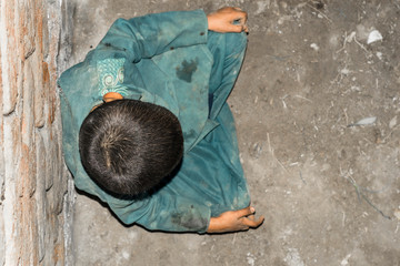 a child wearing dirty clothes and sitting on the ground and feeling so lonely and depressed 