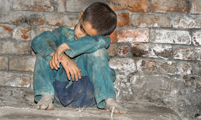 a child wearing dirty clothes and sitting on the ground and feeling so lonely and depressed 