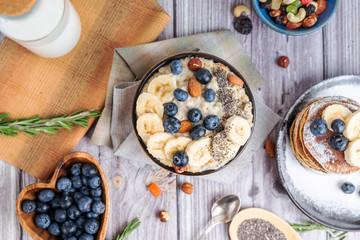 rustic Breakfast pancakes on a plate with blueberries and oatmeal with banana and nuts